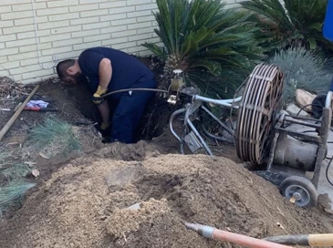 Image of a plumber performing a drain cleaning with snake